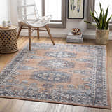 Living room scene with beige Fullarton Performance Rug, white chair, wood side table, and potted plant. Roomscene-Rectangle