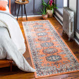 Bedroom scene with a Fullarton Performance Rug in brick red and blue, wooden floors, and a vintage radiator. Roomscene-Runner