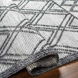 Close-up of the Gada Area Rug. Hand woven texture with a geometric dark gray and light gray pattern. Farmhouse style. Fold