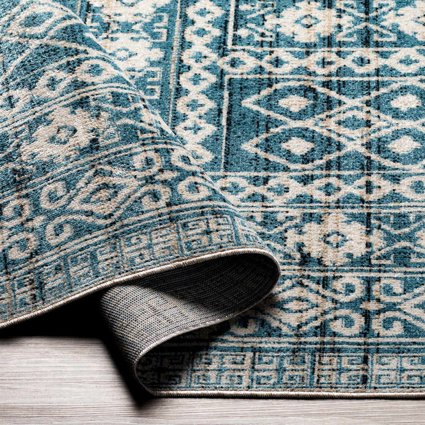 Close up of Gandy Washable Area Rug in blue and cream, showing geometric pattern and texture. Fold