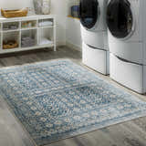 Laundry room scene with white washer/dryer and blue and cream Gandy Washable Area Rug. Roomscene-Rectangle
