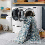 Laundry room scene with Gandy Washable Area Rug partially inside a washing machine. Blue and cream rug. Washing-Machine