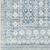Close-up of Gandy Washable Area Rug. Contemporary design in blue, cream, and navy. Geometric and floral pattern. Swatch