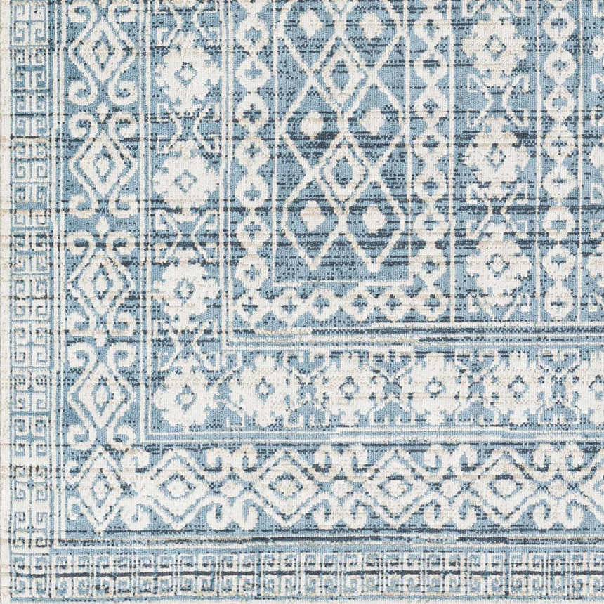 Close-up of Gandy Washable Area Rug. Contemporary design in blue, cream, and navy. Geometric and floral pattern. Swatch