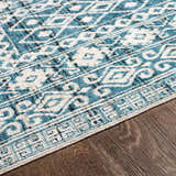 Close up of Gandy Washable Area Rug showing blue, cream, and black contemporary pattern on wood floor. Texture