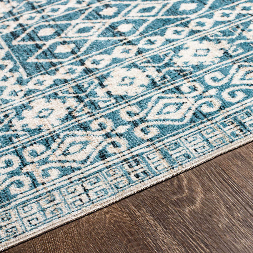 Close up of Gandy Washable Area Rug showing blue, cream, and black contemporary pattern on wood floor. Texture
