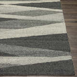 Close-up of the hand-tufted Garlands Area Rug. Wool rug features a contemporary gray, charcoal, and black striped pattern. Front