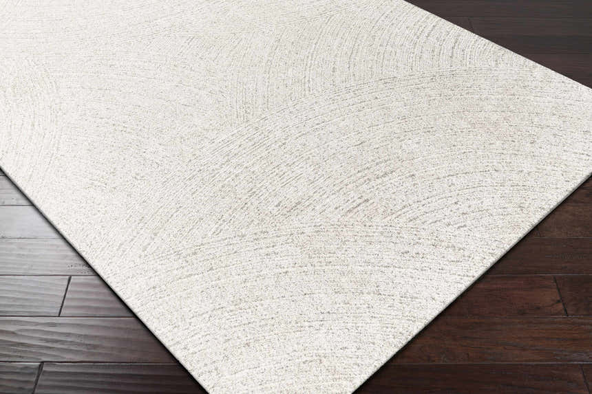 Close-up of the Eaglehawk Luxe Rug, a cream and light beige rug with a subtle, contemporary pattern on dark wood floors. Corner