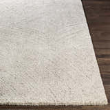 Close-up of the Eaglehawk Luxe Rug, showing a textured cream and light gray pattern on dark wood flooring. Front
