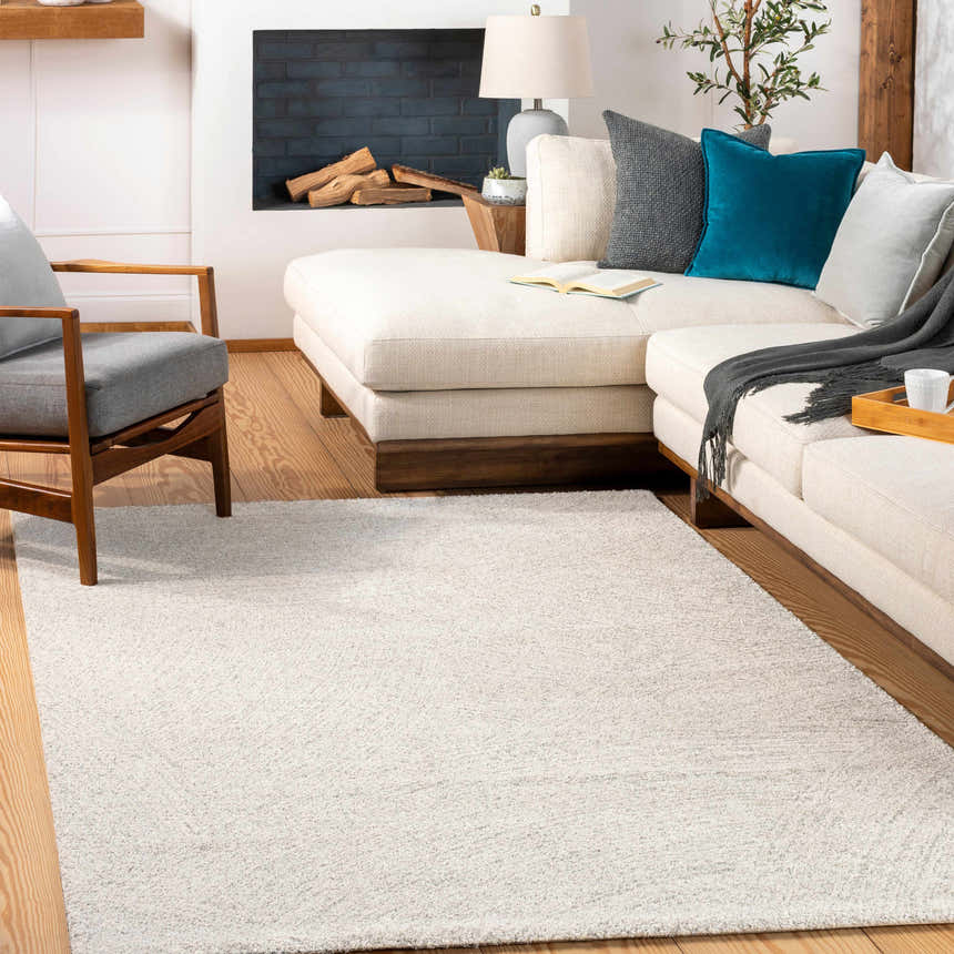 Living room scene with cream sectional sofa and light beige Eaglehawk Luxe Rug on hardwood floors. Roomscene-Rectangle