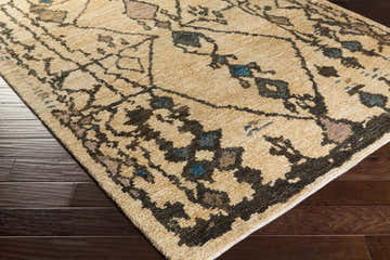 Close-up of the Glide Premium Jute Rug. Hand-knotted rug in beige with aqua, blue, tan, and taupe bohemian-style pattern. Corner