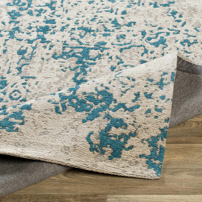 Close-up of Sweeny Beige/Blue Abstract Area Rug showing woven texture and abstract teal and beige pattern. Fold