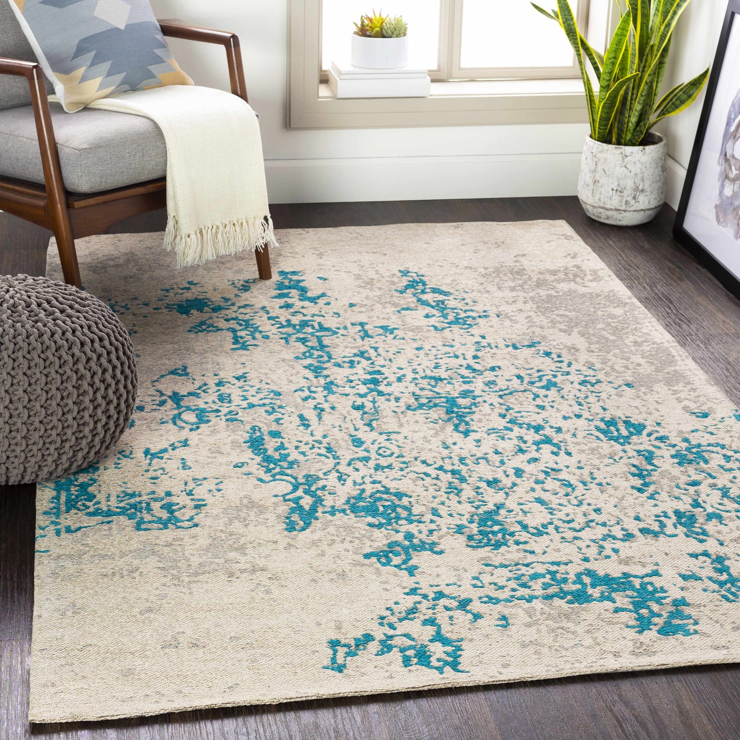 Living room scene with Sweeny Beige/Blue Abstract Area Rug, gray chair, pouf, and wood floors. Contemporary style. Roomscene-Rectangle