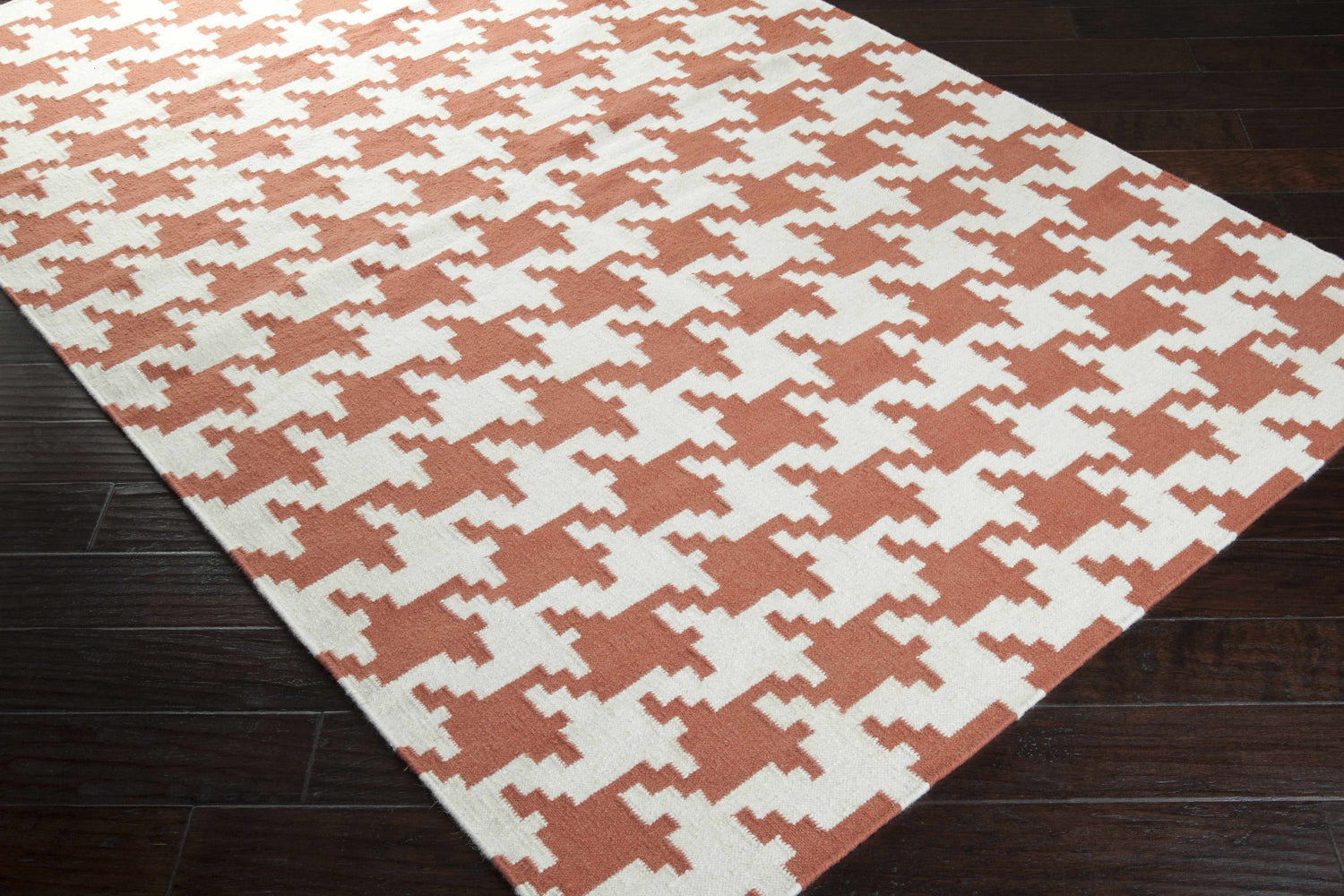 Close-up of the Goldthwaite Area Rug: burnt orange and light beige houndstooth pattern, hand woven wool texture. Corner