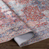 Close-up of the Rust Goma Vintage Area Rug showing its blush, brick red, and blue vintage-style pattern and texture. Fold