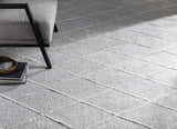 Close-up of light gray Gonvick Area Rug with off-white diamond pattern and textured, hand-knotted viscose pile. Styleshot