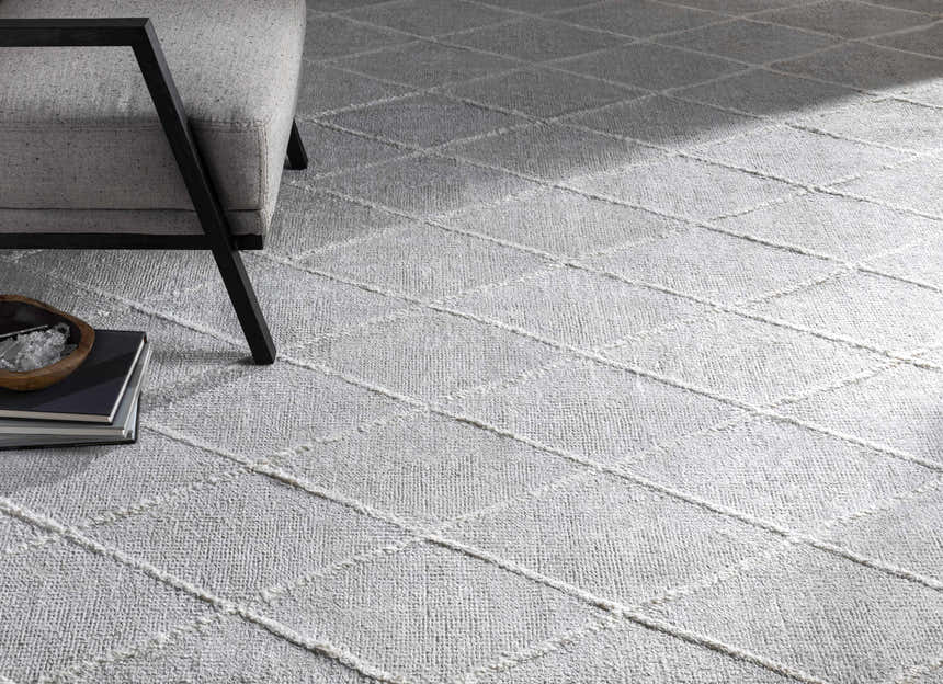 Close-up of light gray Gonvick Area Rug with off-white diamond pattern and textured, hand-knotted viscose pile. Styleshot