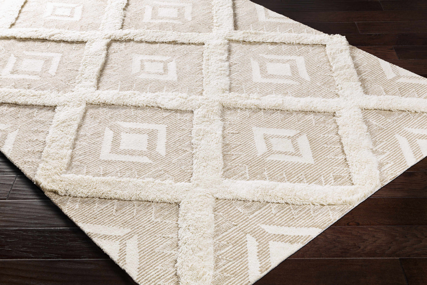 Close-up of the Goodridge Area Rug. Cream and light brown rug with a geometric pattern and tufted grid design. Corner