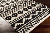 Close-up of the hand woven Gratiot Area Rug. Black geometric patterns on a medium gray background. Bathroom, kitchen, mudroom rug. Corner