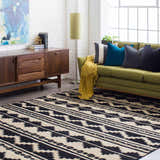 Living room scene with black and gray Gratiot Area Rug, green sofa, wood cabinet, and white brick wall. Roomscene-Rectangle