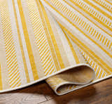 Close-up of the Grian Area Rug. Features a striped pattern in beige, bone, and metallic gold. Machine woven texture. Fold