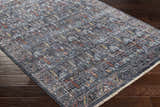 Close-up of the machine-woven Guirang Area Rug. Farmhouse style runner rug in shades of gray, rust, and gold on a wood floor. Corner