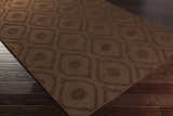 Close-up of the dark brown Hamptonville Area Rug showing its geometric circle and teardrop pattern and wool texture. Corner