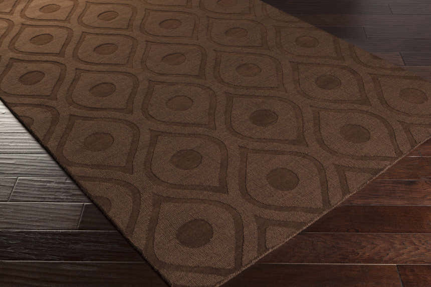 Close-up of the dark brown Hamptonville Area Rug showing its geometric circle and teardrop pattern and wool texture. Corner