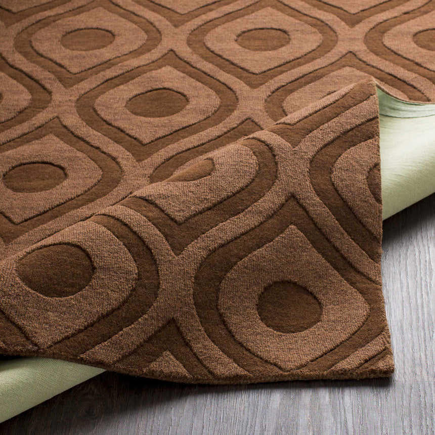 Close-up of the dark brown Hamptonville Area Rug showing its geometric pattern and hand-loomed texture. Fold