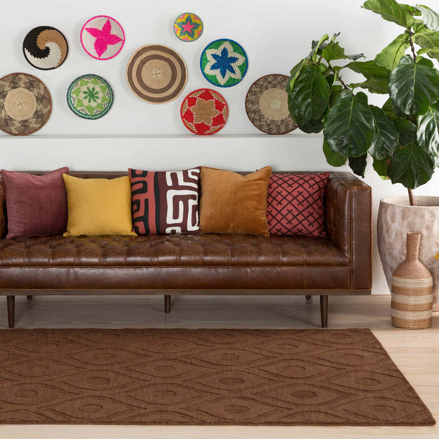 Living room scene with a brown leather sofa, colorful wall decor, and the Hamptonville Area Rug in dark brown. Roomscene-Rectangle