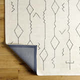 Close up of the Hanny Area Rug. Beige wool rug with a geometric diamond and line pattern. Hand tufted texture. Fold