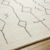 Close up of the beige Hanny Area Rug showing the hand tufted wool texture and geometric black line pattern. Texture