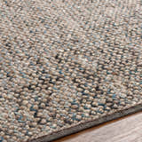 Close-up of the hand woven Hansell Area Rug. Charcoal, ice blue, and ivory wool rug texture. Texture