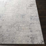 Close-up of the Hardeeville Area Rug showing a textured, abstract pattern in shades of gray and ivory on a dark wood floor. Front