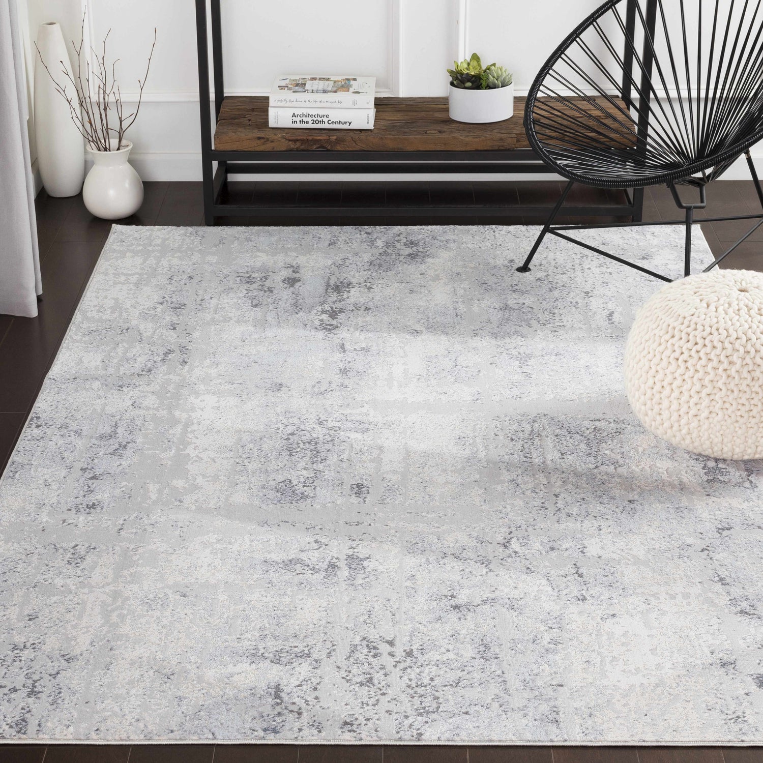 Living room scene with a light gray Hardeeville Area Rug, black chair, and white pouf. Abstract pattern. Modern style. Roomscene-Rectangle