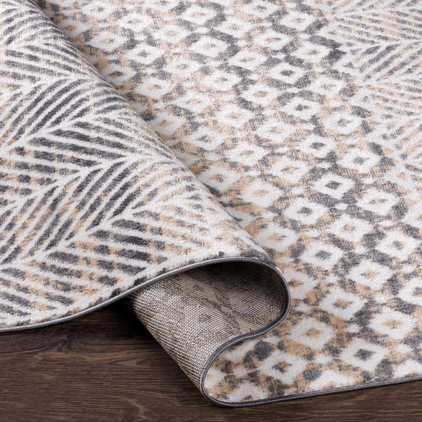 Close-up of the Hassocks Area Rug showing charcoal, cream, tan diamond pattern and backing on dark wood floor. Clearance rug. Fold