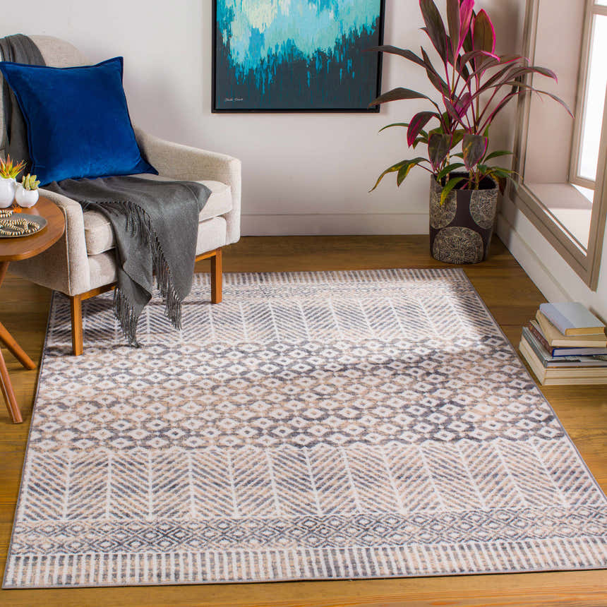 Living room scene with a Hassocks Area Rug in charcoal, cream, and tan, styled with a chair, side table, and artwork. Roomscene-Rectangle