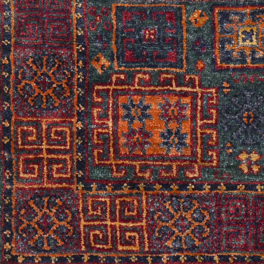 Close-up of the Herman Jute Carpet, showcasing its hand-knotted texture and traditional pattern in burnt orange, red, and dark green. Swatch