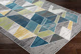 Close-up of Hessel Green Triangles Area Rug showing its geometric pattern and colors: teal, green, yellow, gray, and white. Corner