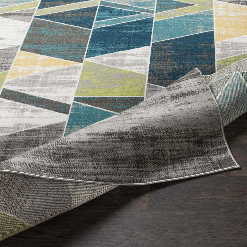 Close-up of the Hessel Green Triangles Area Rug showing its charcoal, gray, green, teal, yellow geometric pattern. Fold