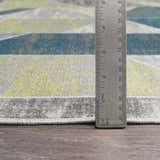 Close-up of Hessel Green Triangles Area Rug showing geometric pattern, teal, green, gray, and rug thickness with ruler. Pile