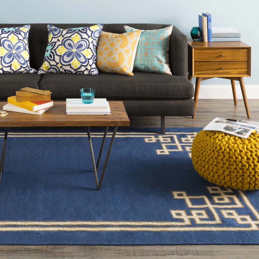 Living room scene with dark blue Hinckley Area Rug, gray sofa, wood coffee table and yellow pouf. Roomscene-Rectangle