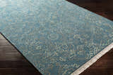 Close-up of the Hinkle Teal Premium Wool Carpet showing its teal color and light brown and oatmeal floral pattern. Corner