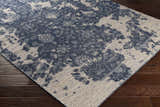 Close-up of the hand-knotted Holmes Carpet - Clearance. Ivory, navy, and slate wool rug with a vintage bohemian design. Corner