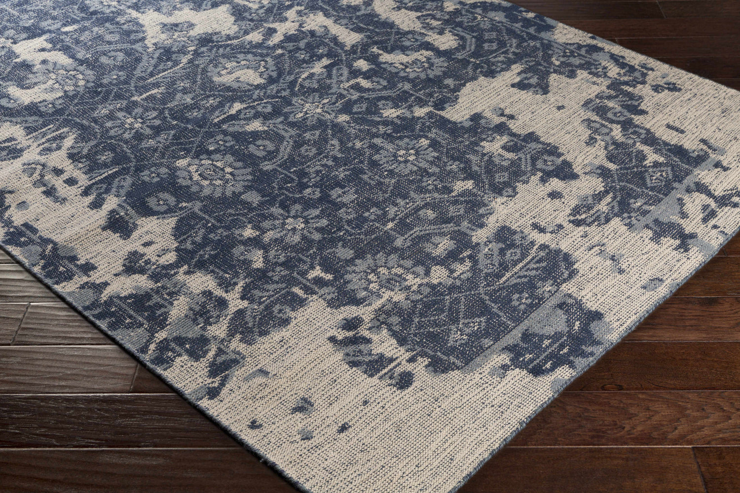 Close-up of the hand-knotted Holmes Carpet - Clearance. Ivory, navy, and slate wool rug with a vintage bohemian design. Corner