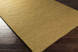Close-up of the light brown Hensler Area Carpet showing its hand woven texture on dark wood floors. Corner