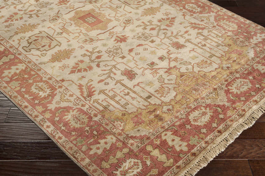 Close-up of the hand-knotted Hobart Area Rug. Features a traditional pattern in brown, burgundy, and light brown tones. Corner