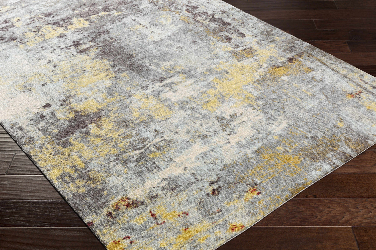 Close-up of the Hobson Abstract Area Rug showing its black, mustard, and gray contemporary design on a dark wood floor. Corner