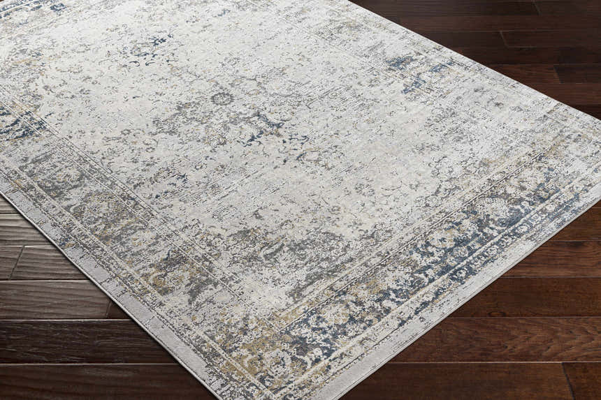 Close-up of the Holcombe Area Rug in charcoal, cream, and gray, showing its traditional design and machine-woven texture. Corner