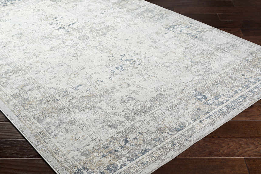 Close-up of the Holcombe Area Rug, a machine-woven rectangle with charcoal, cream, gray, and tan Oriental-style patterns. Corner